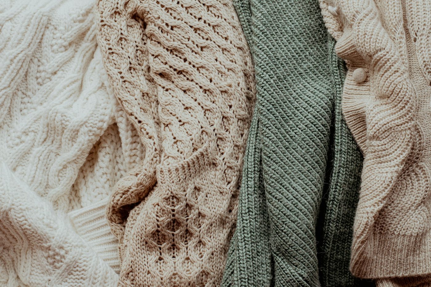 Cable and rib knits in cream, sand and sage laid side by side.