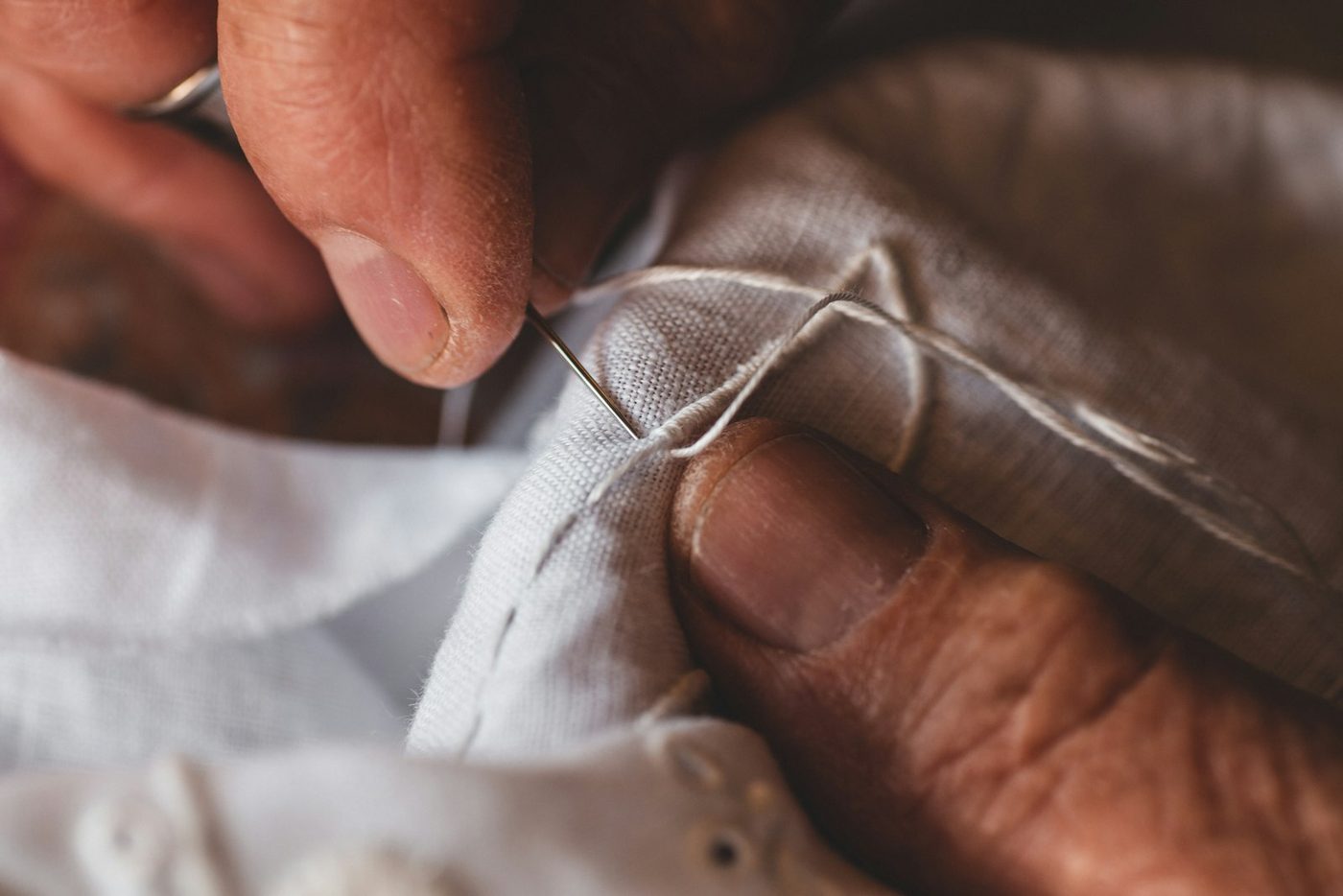 Hands sewing white fabric